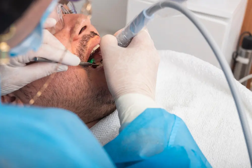 Five reasons why Cavitron Ultrasound Dental Scaling can Work Better for You 1 Dentist using an ultrasonic scaler, or détartreur dentaire ultrason, to clean a reclined patient's teeth